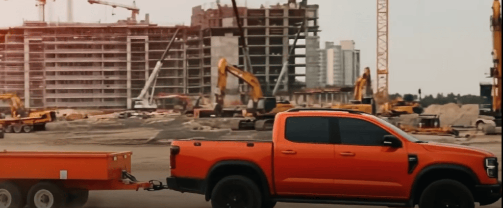 Orange Rely R8 towing a trailer at a construction site